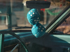 Blue fuzzy dice hanging from a rearview mirror. 